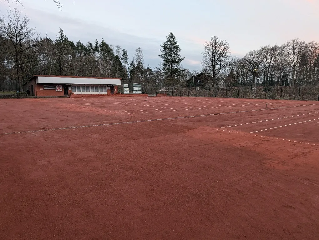 Sandplätze mit frischen weißen Linien in der Abenddämmerung, im Hintergrund das Vereinsheim.